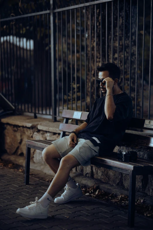 a man sitting on top of a bench talking on a cell phone