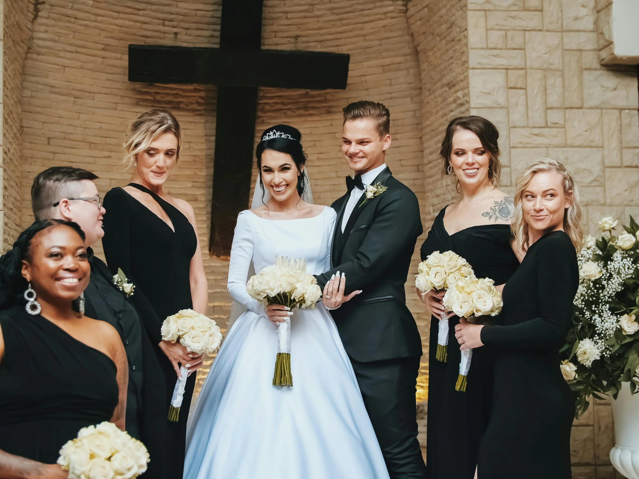 a bride and groom stand together with other people