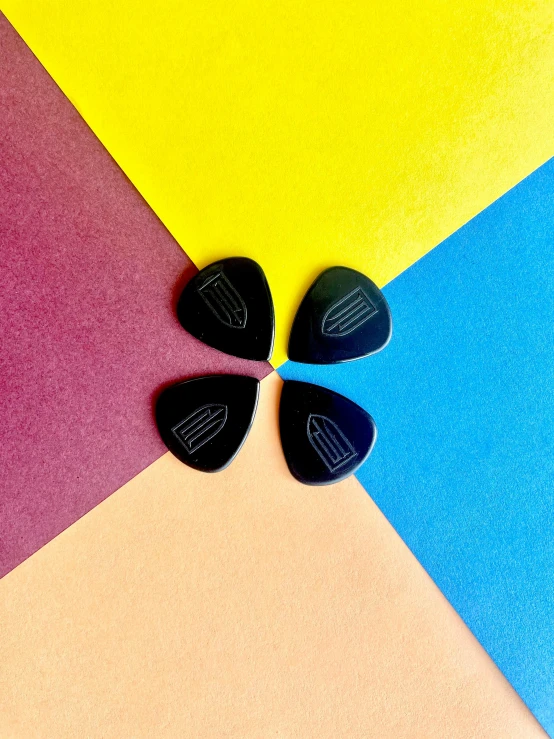 three guitar picks with a blue, green, red and yellow umbrella