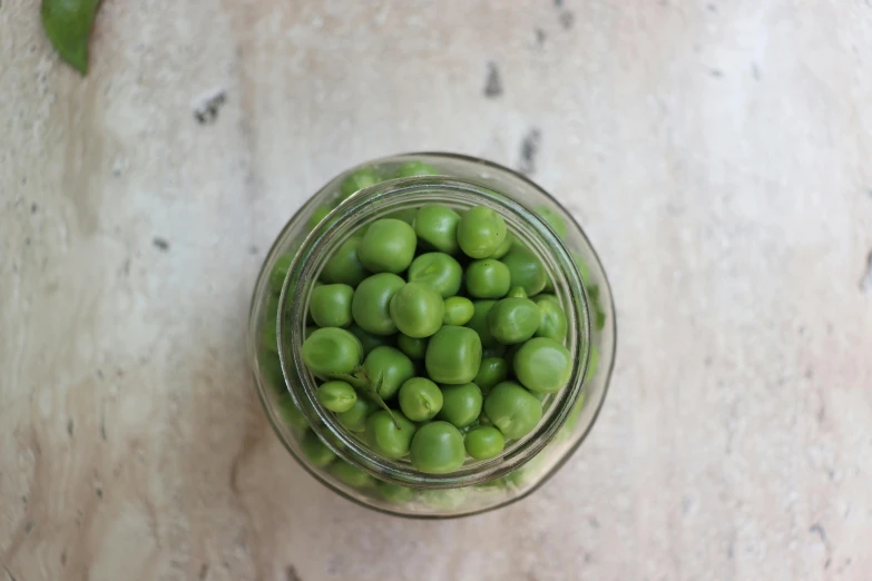 a small glass jar with green peas in it