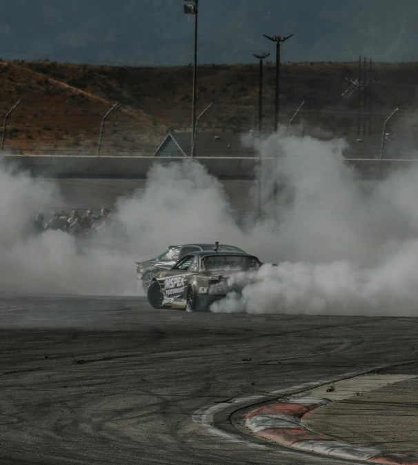 a silver car on track with smoke trailing from the tires