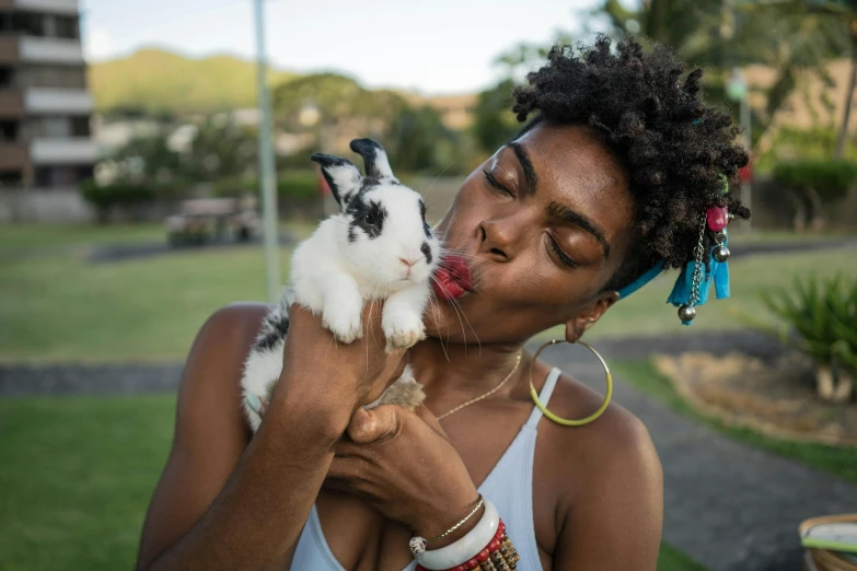 a woman holds a little bunny while licking it