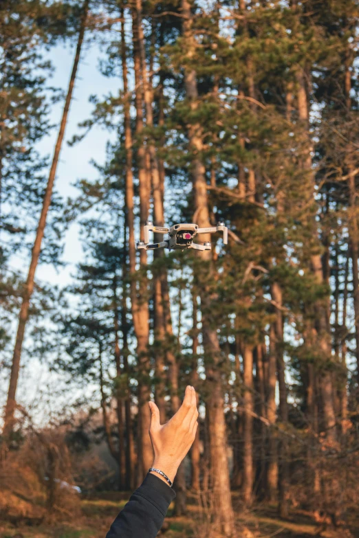 the man holds out his hand to fly a small white aircraft in the air