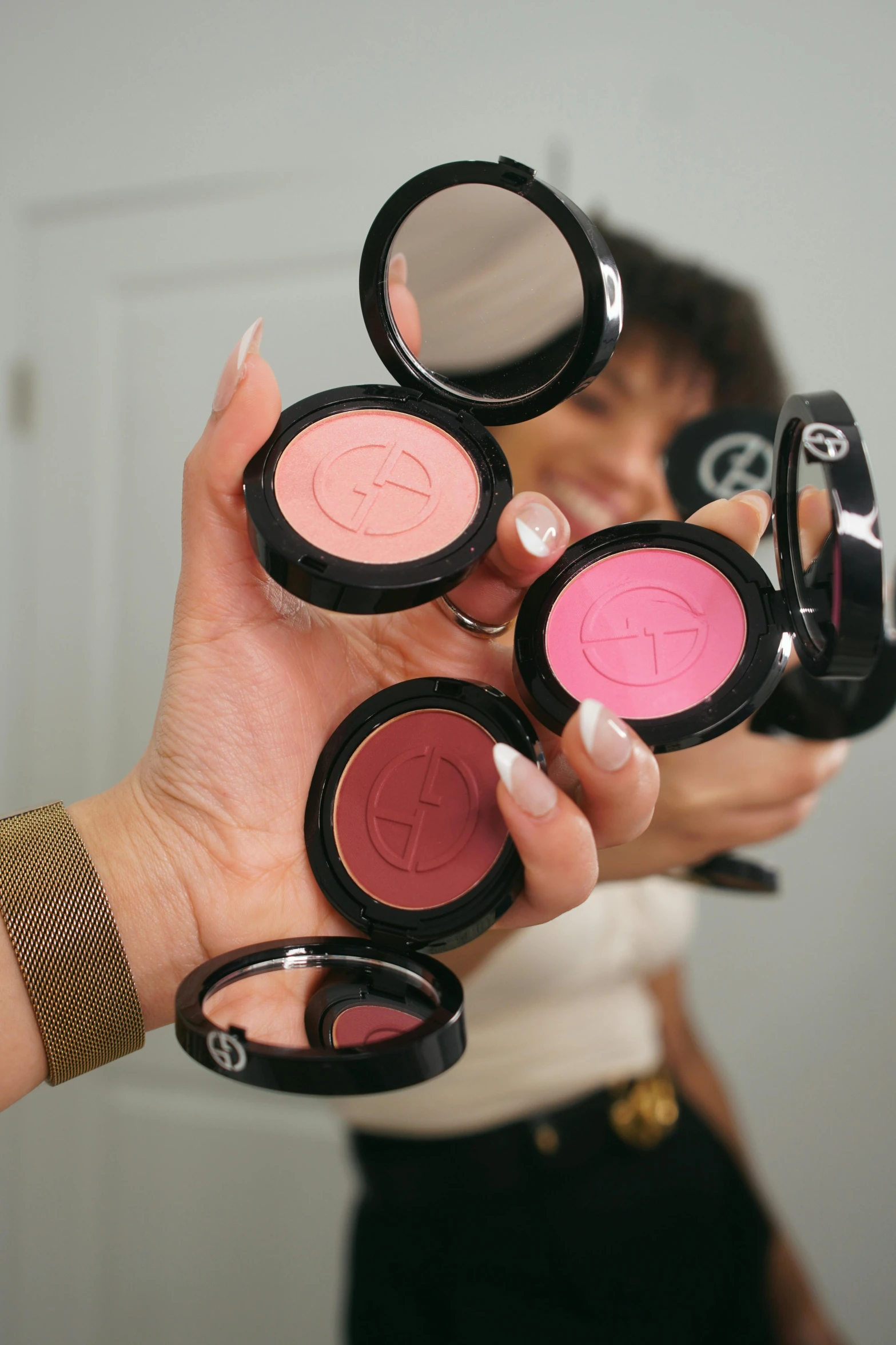 a woman holding up six mac blushes