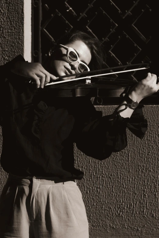 a person wearing sunglasses holding a violin outdoors