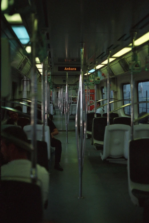 a train car is crowded with passengers and metal handrails