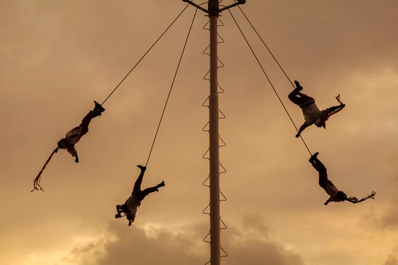 people climbing down on pole that is very high