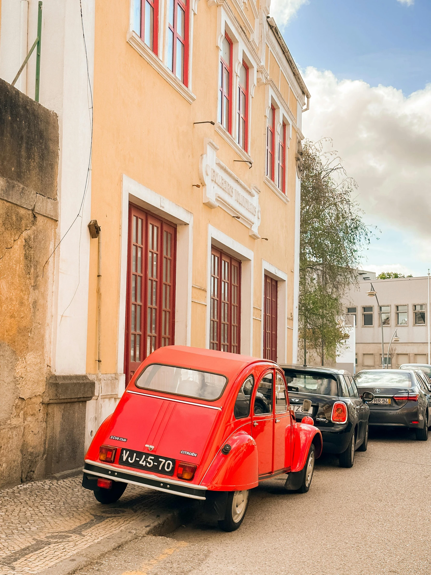 a small red car parked next to a yellow building