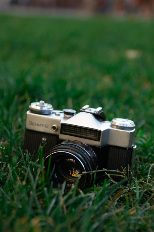 a camera is laying in the grass and is facing away