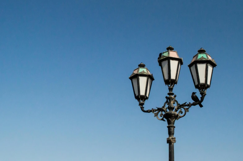 three old fashioned street lamps against a bright blue sky