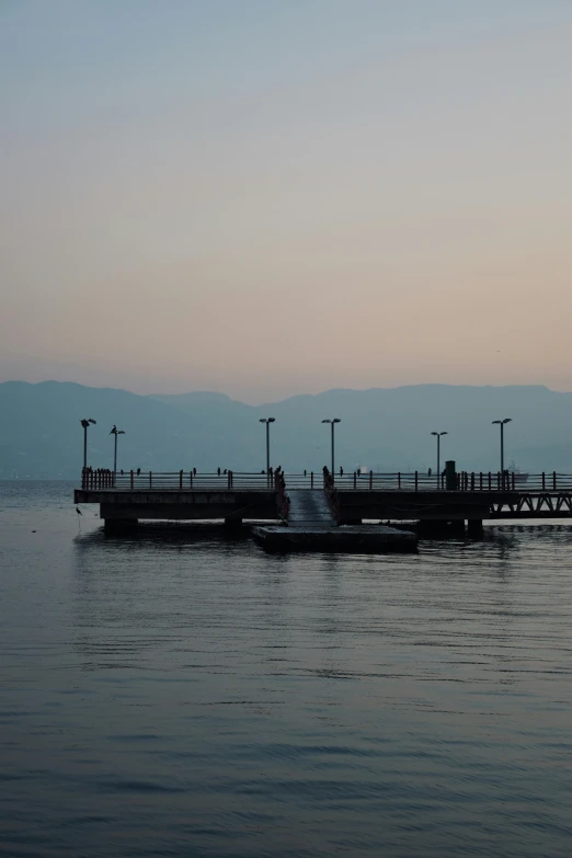 a pier at the water's edge, with light poles in the background