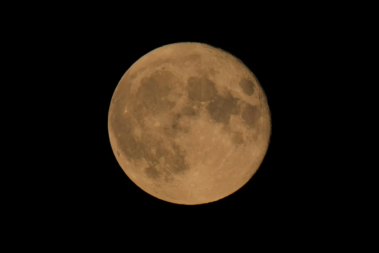 a full moon shines yellow in the night sky