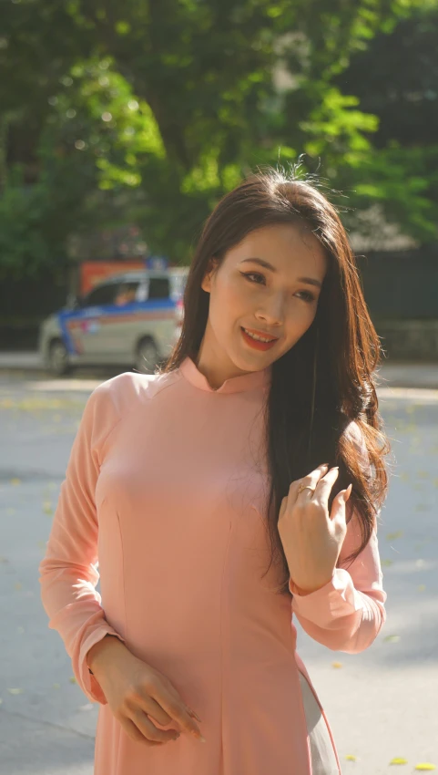 a beautiful woman wearing a pink dress standing near a parking lot