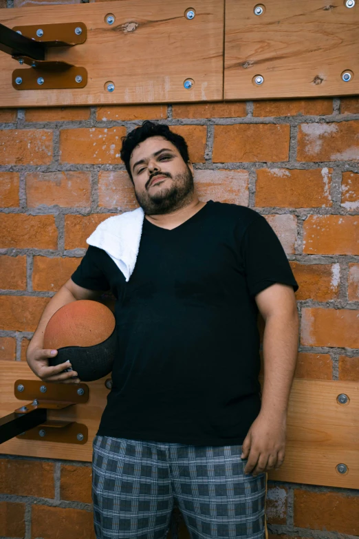 an overweight man in a black shirt poses with his basketball