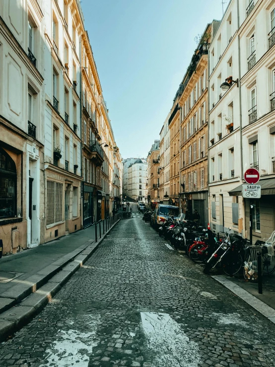 a city street with buildings, motor bikes and a stop sign