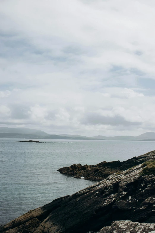 a man in shorts standing on top of rocks near the ocean