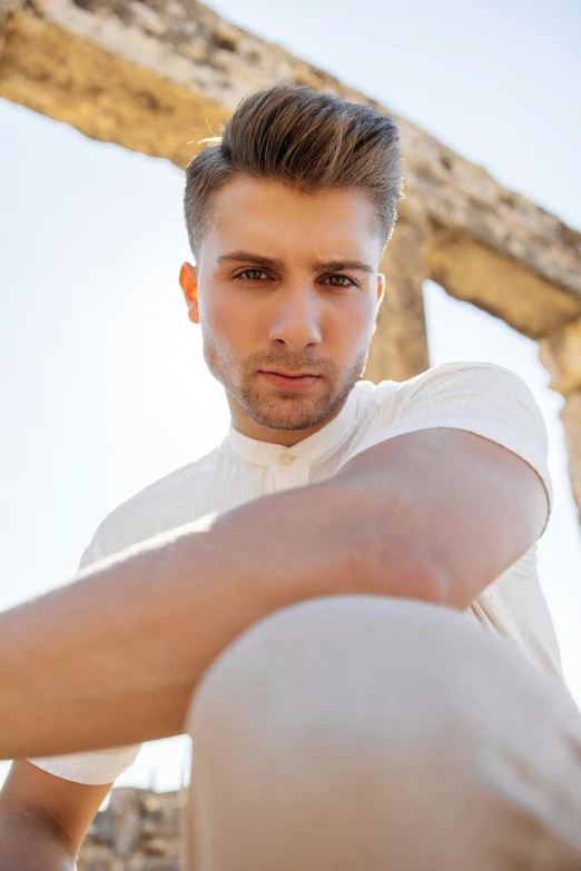 a young man leaning on the top of a stone structure