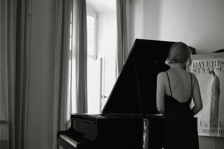 a woman standing at a piano in front of a window