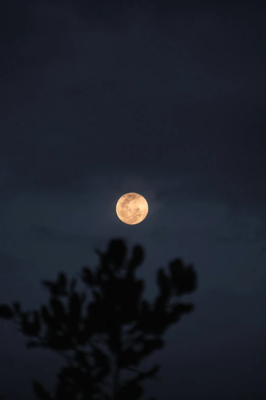 full moon seen through clouds in the distance