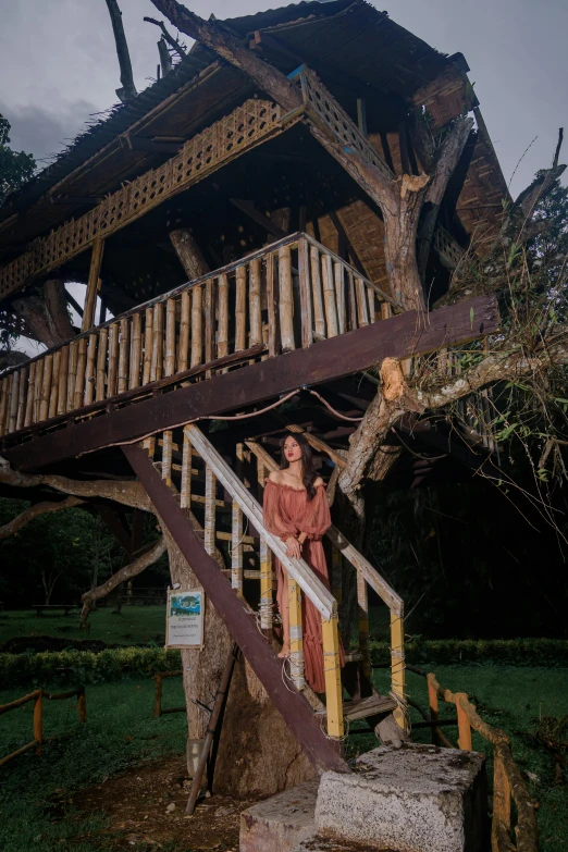 a woman is standing on a handrail in a wooded area