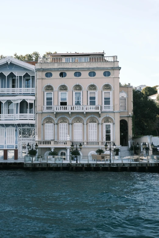 a tall building on the edge of water next to houses