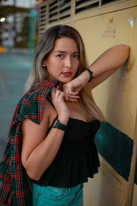 a beautiful woman in black shirt standing next to wall