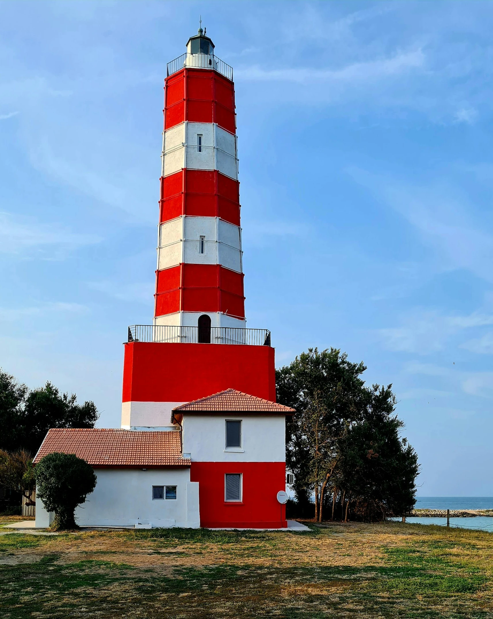 red and white building sitting in front of water with trees on top