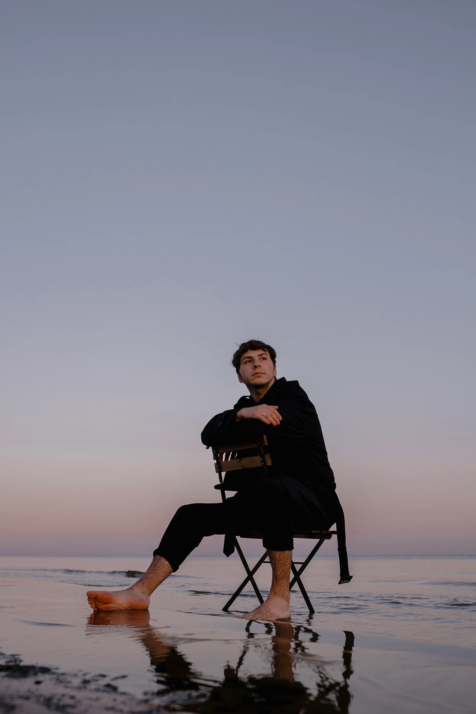 man sits in a chair while looking out over water