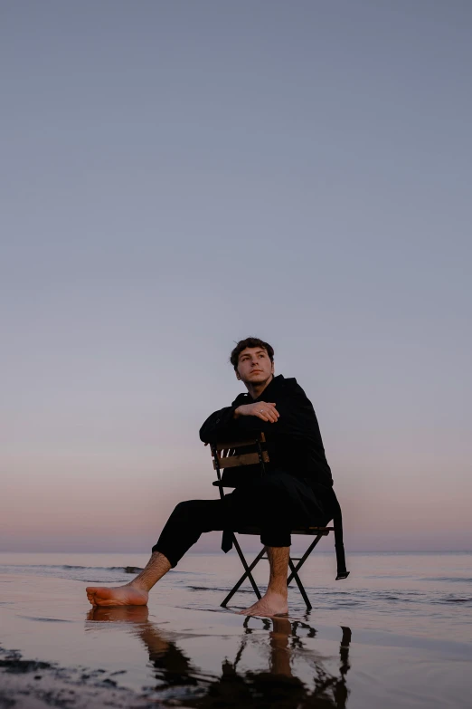 man sits in a chair while looking out over water