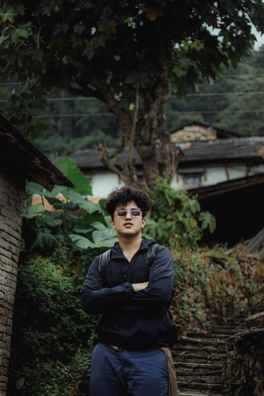 man wearing dark blue shirt, pants and glasses looking off to the left