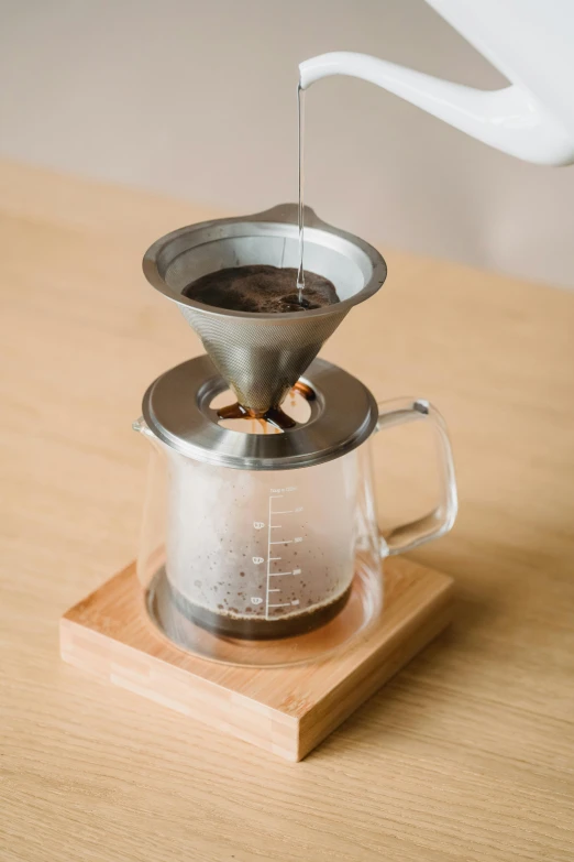 a person pours boiling from a glass pitcher into a cup