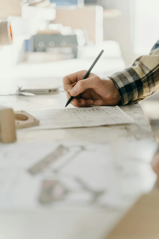 a person writes on paper next to an object that looks like a computer