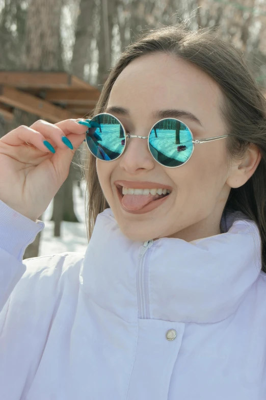 the girl wearing the snow coat is holding some sunglasses