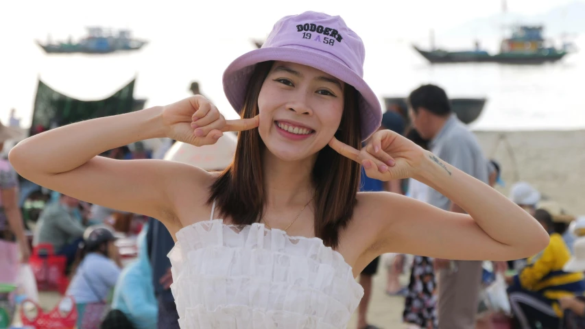 a young woman holding onto her hat as she smiles
