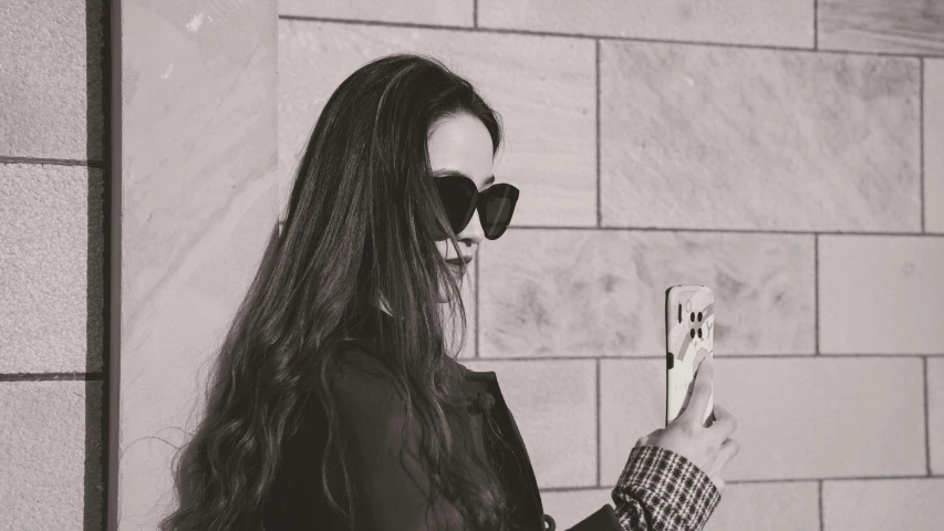 a woman wearing sunglasses looking at her phone