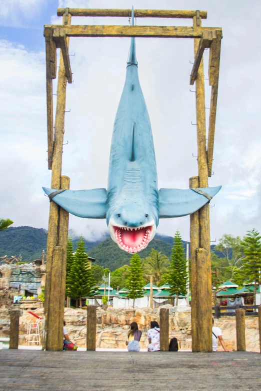 there is a fake shark hanging from a wooden pole