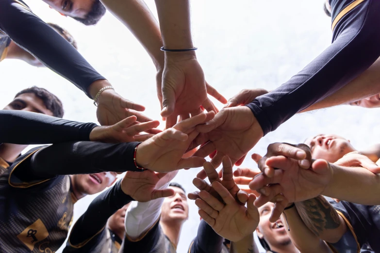 many hands stacked together with a large group of people in the background