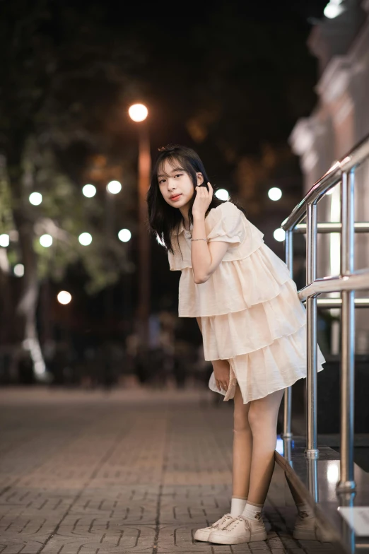 a girl in an elegant dress stands on the edge of a railing, talking on her cell phone