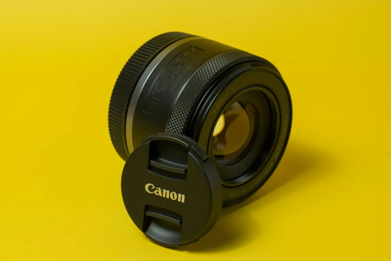 camera lens resting on yellow background with lens cap