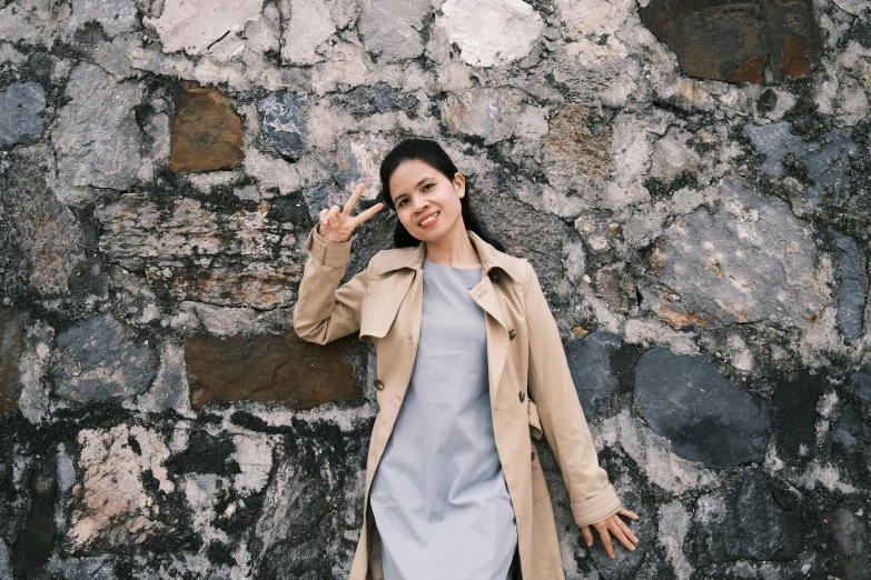 a woman leaning against a stone wall talking on her cellphone