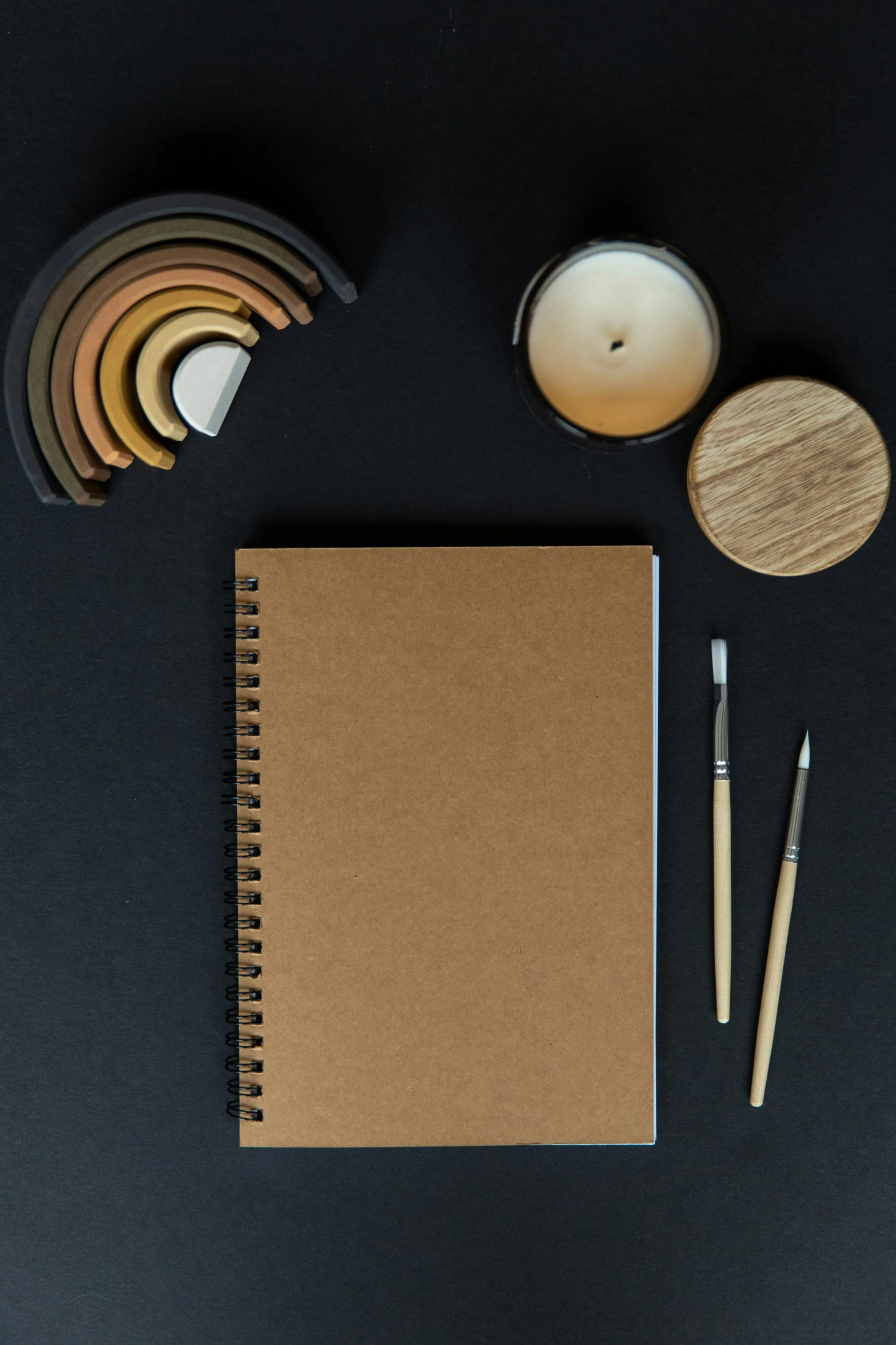 a table that has a book, pen, coaster and two candles