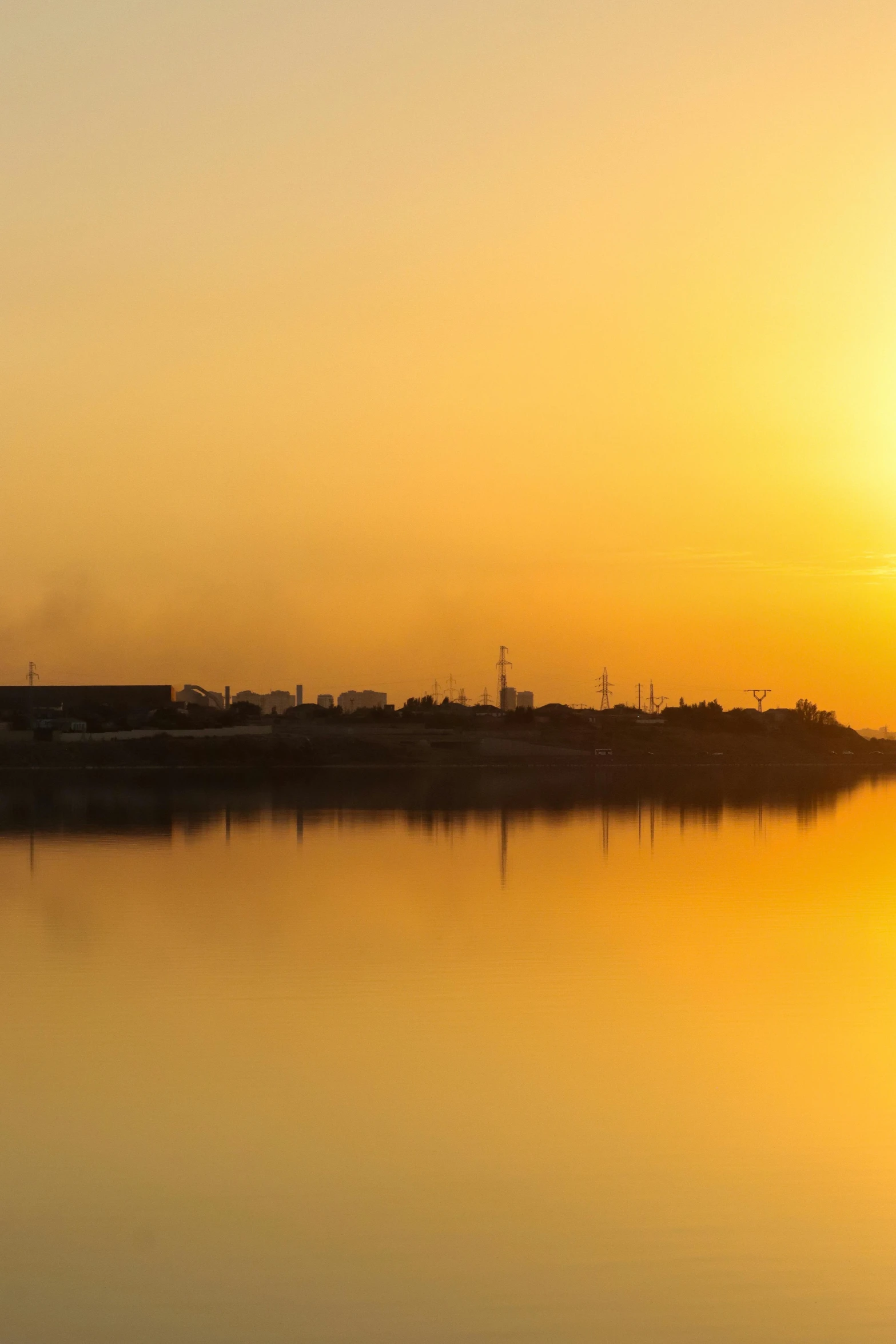 an airplane flying over water at sunset with a bridge in the background