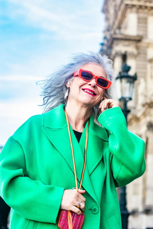 a woman in green coat with sunglasses on phone