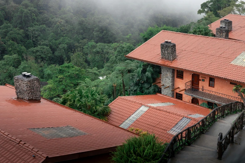 an aerial view of a red house surrounded by trees and foliage