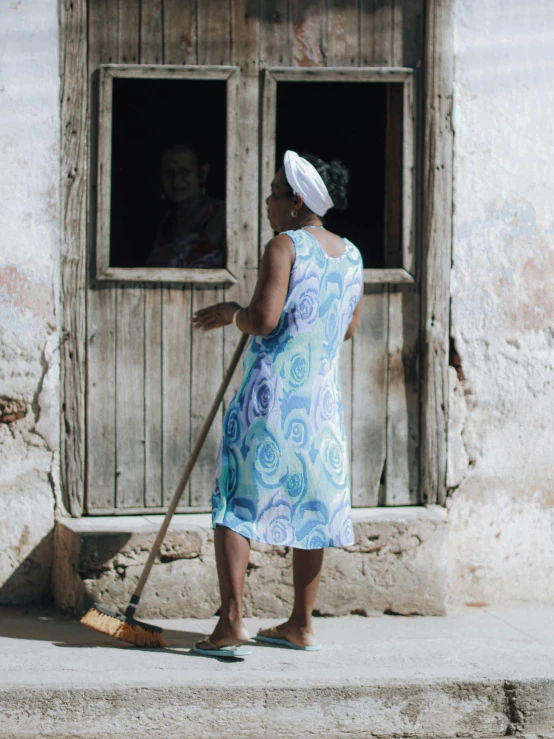 a woman with a cleaning broom on a porch