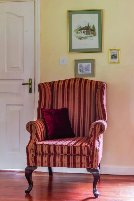 a living room with a striped chair and paintings on the wall