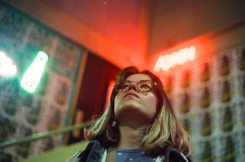 a woman with glasses stares upward into the sky