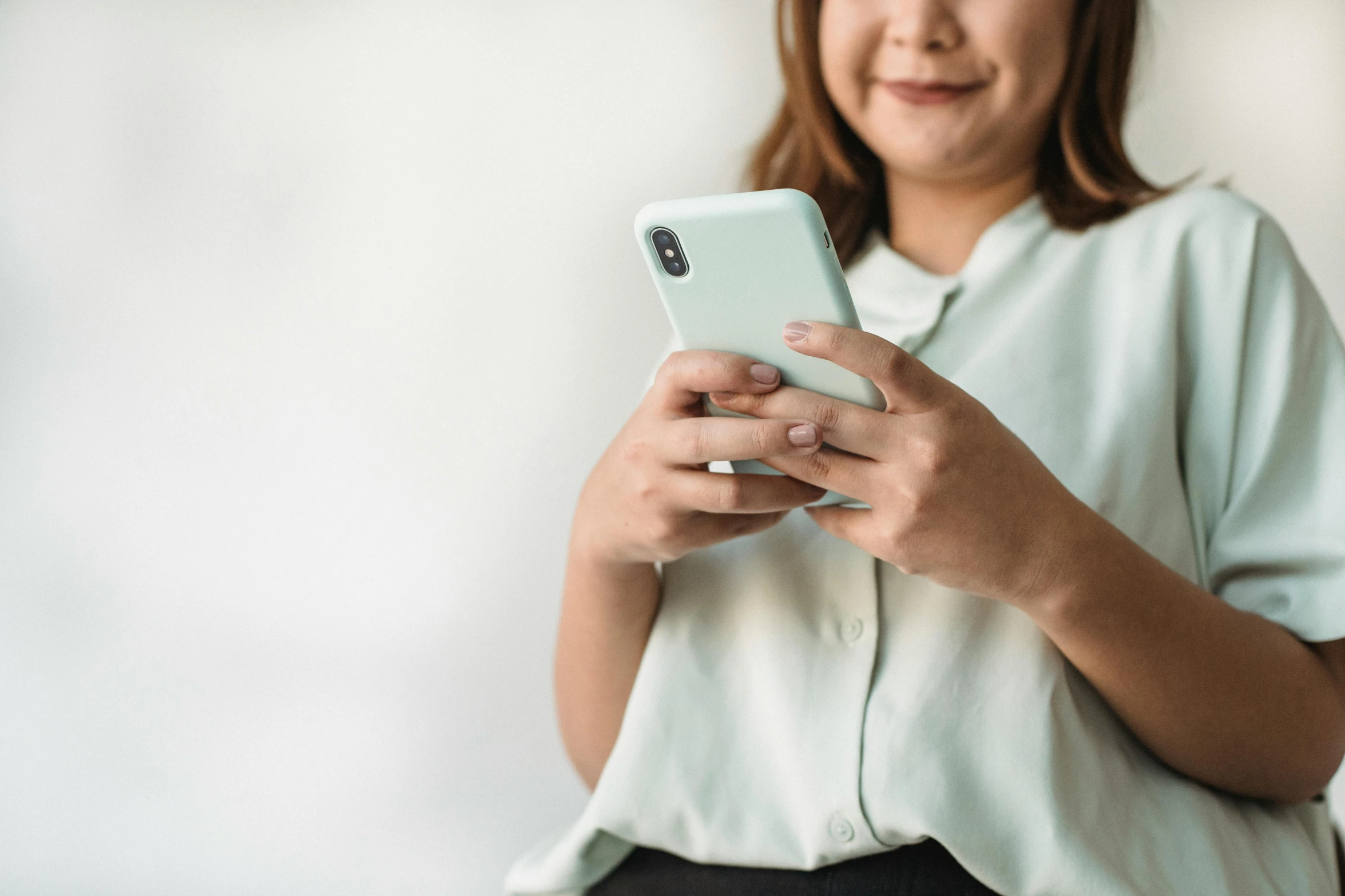 an asian woman wearing a polo shirt holding her cell phone