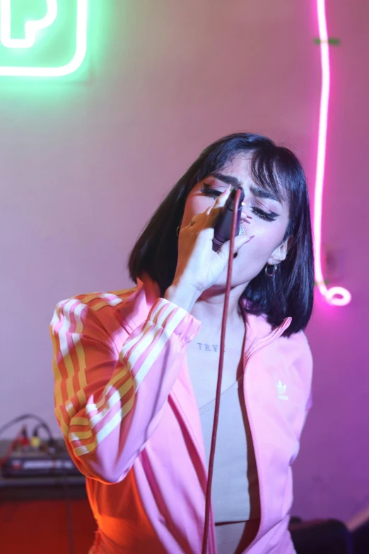 a woman singing into a microphone in front of neon lights