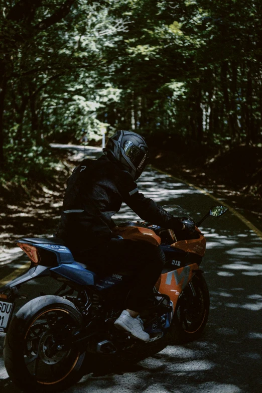 a person riding on the back of an orange and black motorcycle